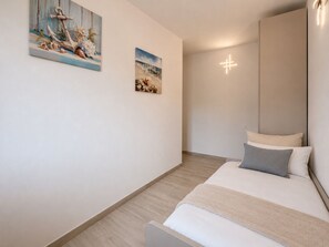 Ein Schlafzimmer mit einem Bett, einem Nachttisch, einer Wandleuchte und zwei Bildern.