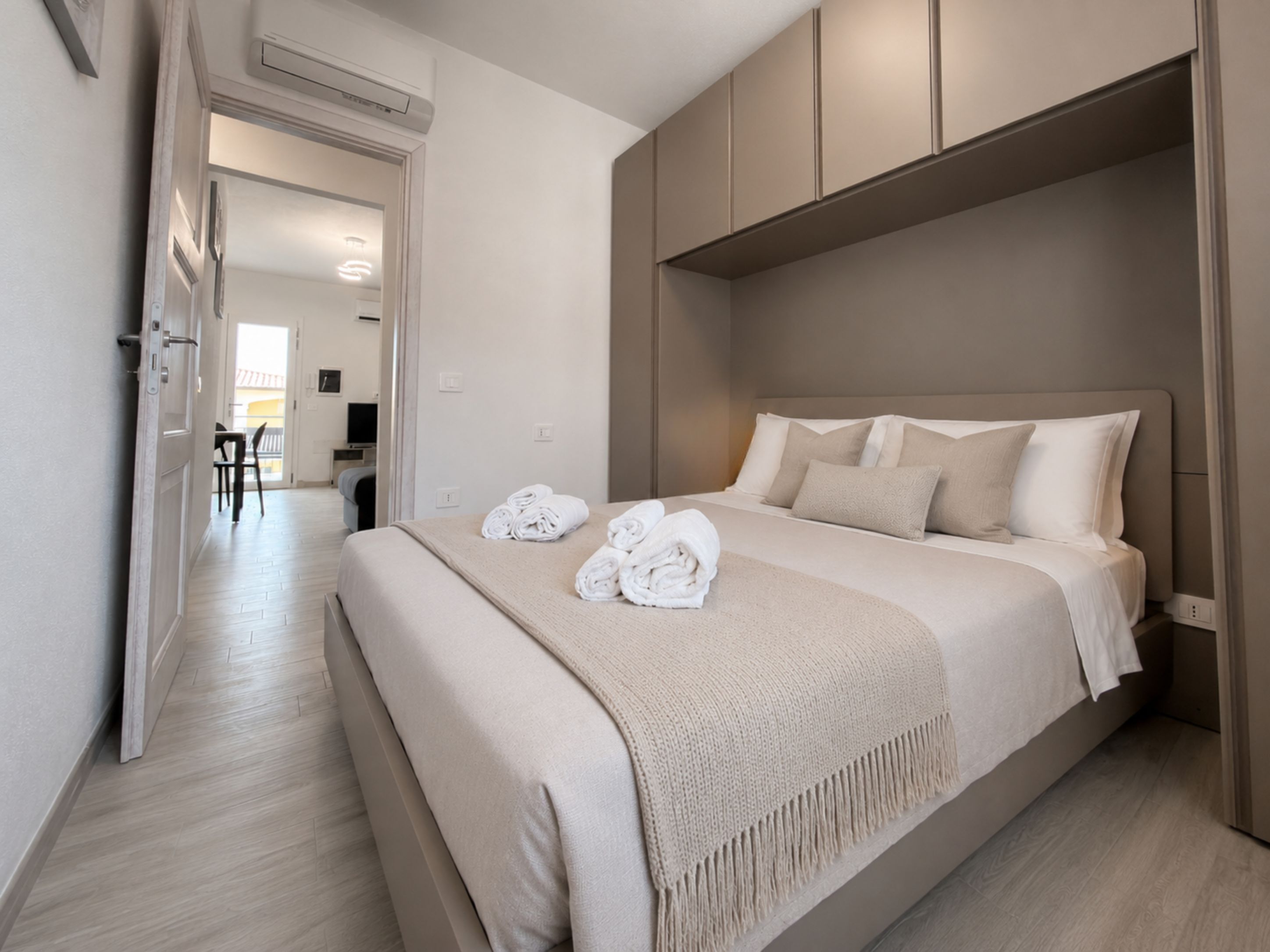 Moderni hotellihuone, jossa on suuri sänky, sisäänrakennettu vaatekaappi ja erillinen oleskelualue.