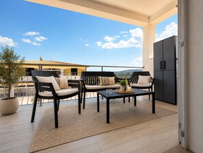 Ein Balkon mit Gartenmöbeln, einem Blumentopf und Blick auf Gebäude im Hintergrund.
