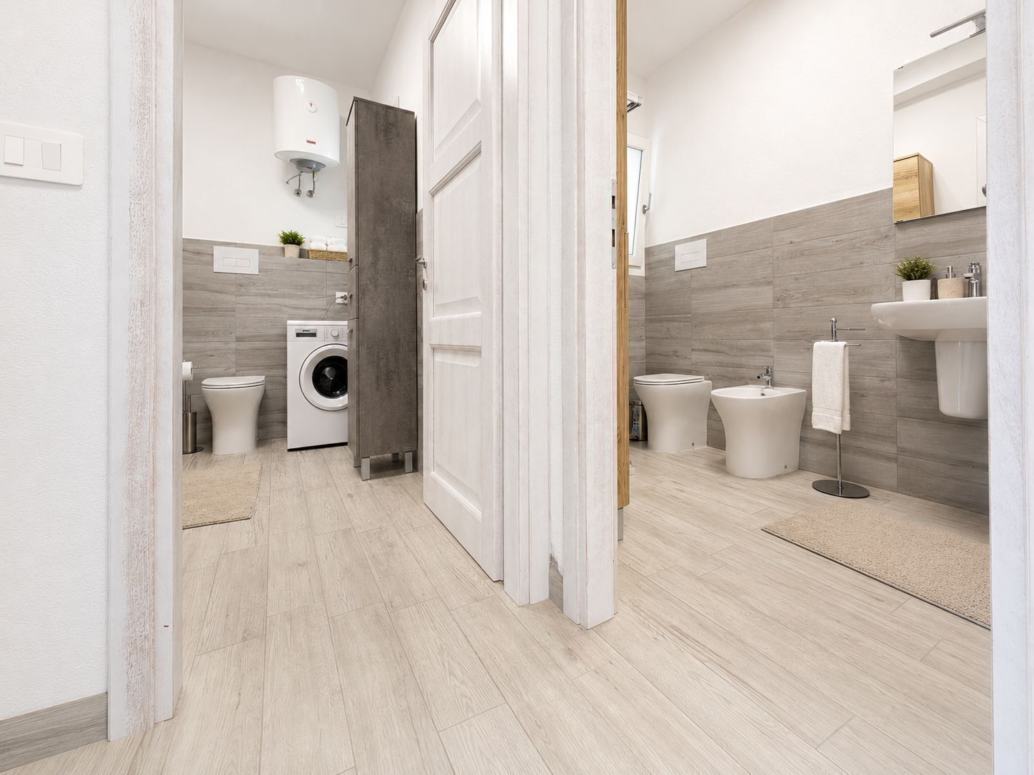 Ein modernes Badezimmer mit Waschmaschine, Bidet und einem großen Spiegel.