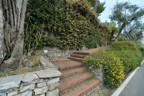 A stone staircase with brick steps leading up to a stone wall, surrounded by greenery and yellow flowers. - The Bay Garden Apartment- Santa Margherita Ligure (Santa Margherita Ligure)