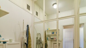 Ein Zimmer mit einem großen Spiegel, Holzboden, einem roten Sessel, einer Leiter und einem Schreibtisch mit Regalen.