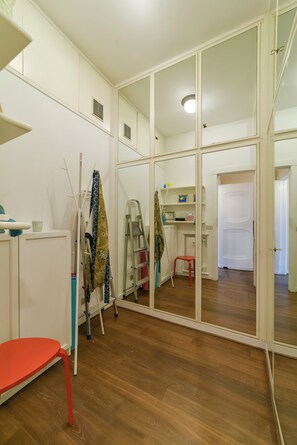 A room with a large mirror, wooden flooring, a red chair, a ladder, and a desk with shelves. - The Bay Garden Apartment- Santa Margherita Ligure (Santa Margherita Ligure)