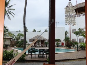 A pool area with lounge chairs and a thatched-roof structure.