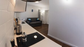 Un espai vital compacte amb petita cuina, un sofà gris i una màquina de cafè.