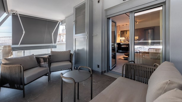 Un balcon moderne avec un canapé, des chaises et une table.