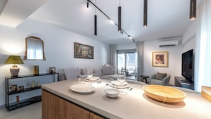 Une cuisine moderne dotée d’un îlot central, de luminaires suspendus et d’un coin repas avec un canapé et une table.