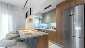 Une cuisine moderne dotée d’un réfrigérateur en acier inoxydable, de meubles en bois et d’un coin bar avec des tabourets.