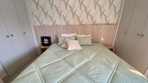 Una camera da letto con un letto, due comodini, uno specchio e una parete decorata con un motivo a foglia.