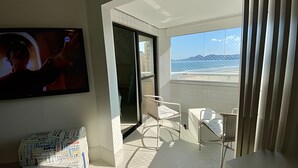 A hotel room with a balcony, a television, and a chair.
