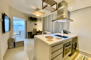 Uma cozinha moderna com ilha central, forno embutido e máquina de lavar.