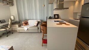 Una moderna camera d'albergo con divano, scrivania e angolo cottura.