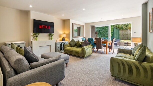 Ein Wohnzimmer mit Flachbildfernseher, Kamin, Essbereich und einer großen Schiebeglastür nach draußen.