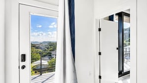En modern inredning med en skjutdörr i glas som leder ut till en balkong med utsikt över landskapet.