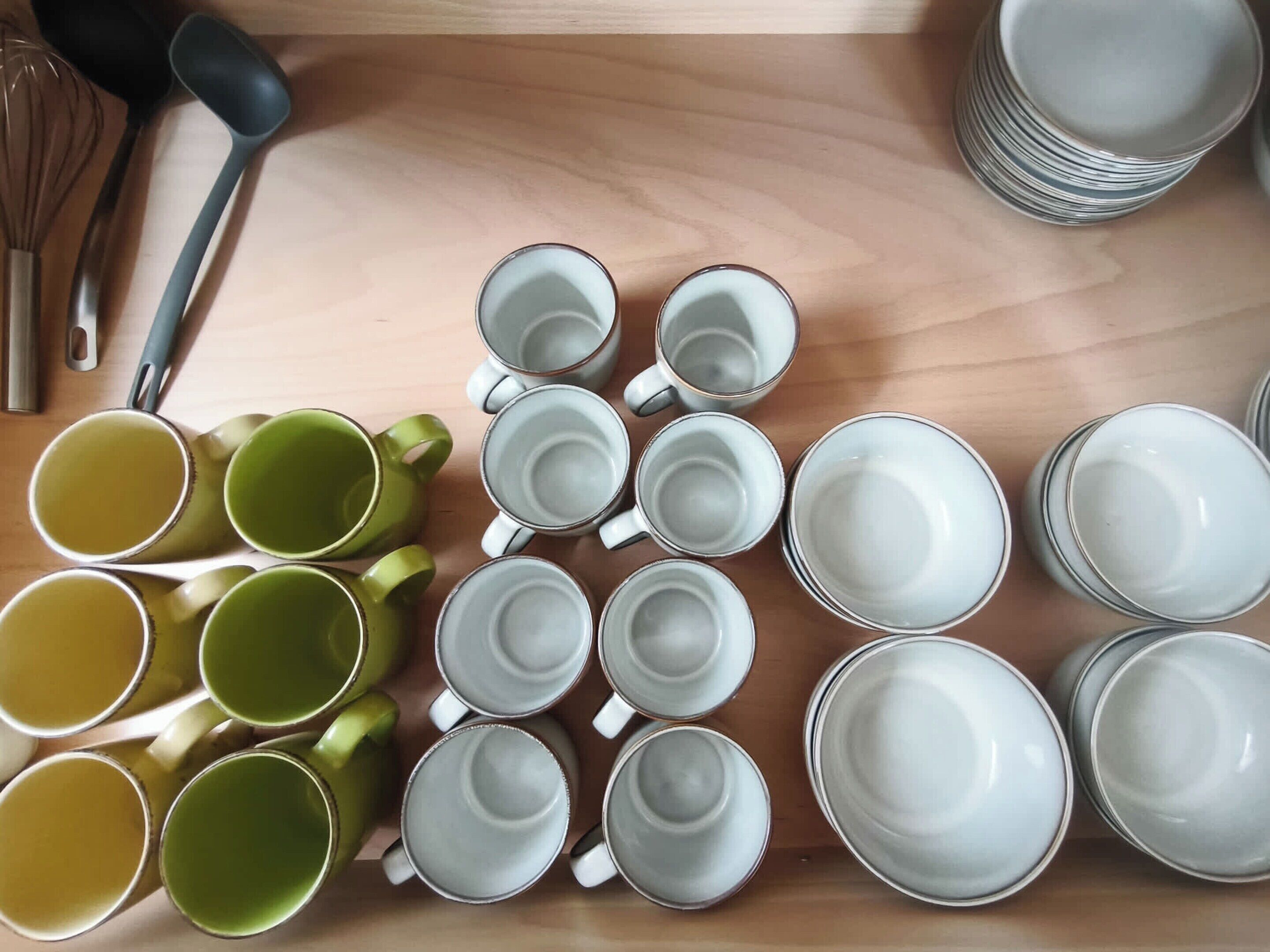 A wooden table with various ceramic mugs and plates arranged on it.