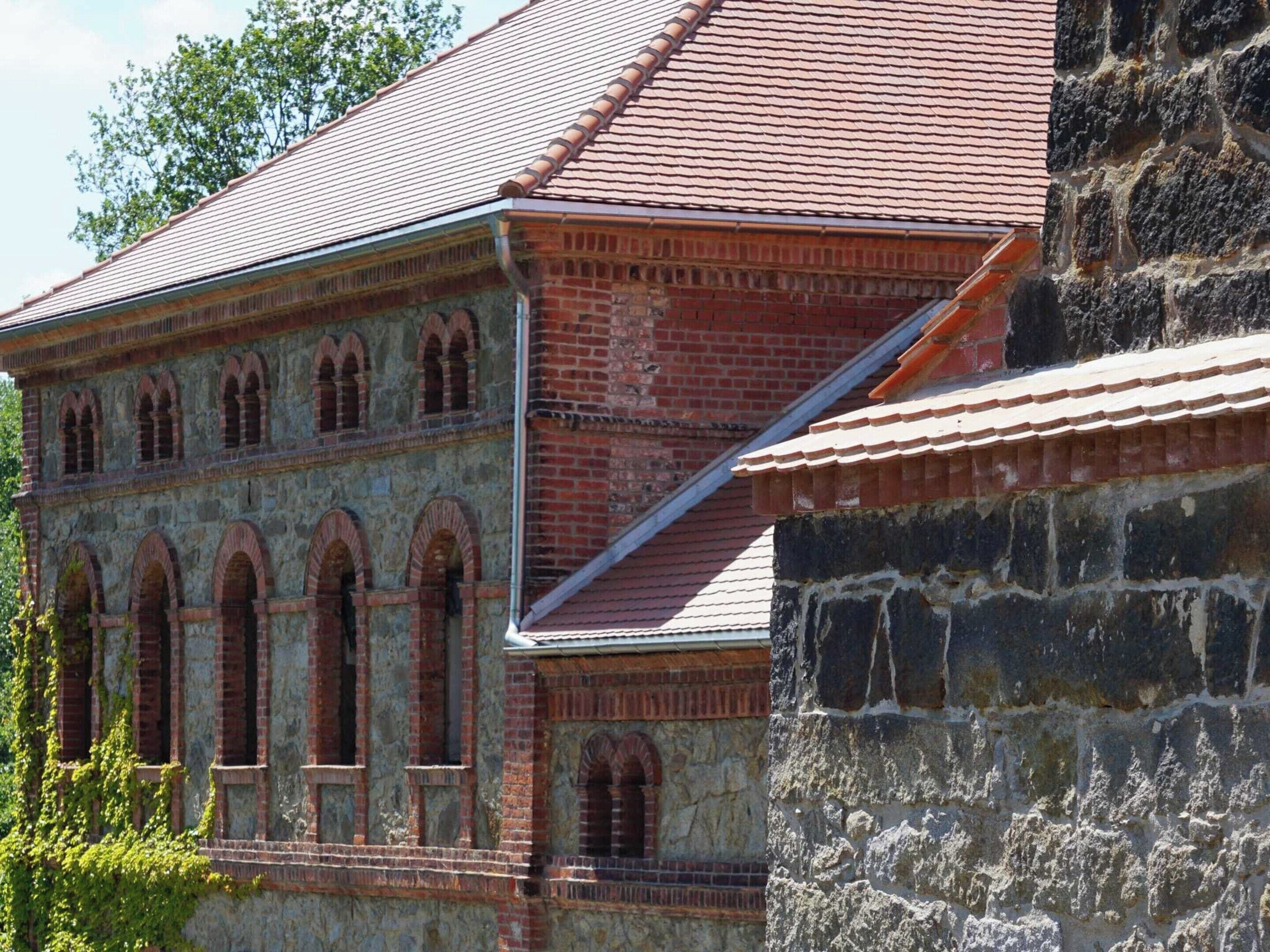 Ein historisches Gebäude mit Rundbogenfenstern und einem roten Ziegeldach.