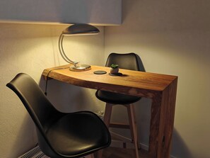 A small wooden table with a lamp, two black chairs, and a small plant. - Wellness-apartment mit Eigener Sauna und Whirlpool (Grossharthau)