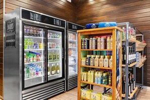 Een minibar met een koelkast vol drankjes en een plank met alcoholische flessen.