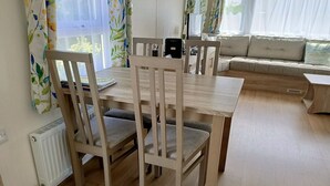 Ein Essbereich mit Holztisch und Stühlen, einem Heizkörper und einem Fenster mit Vorhängen.