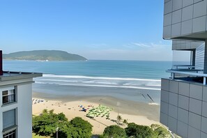Blick auf einen Strand von einem Gebäude mit Balkon mit Meerblick und einer entfernten Insel.