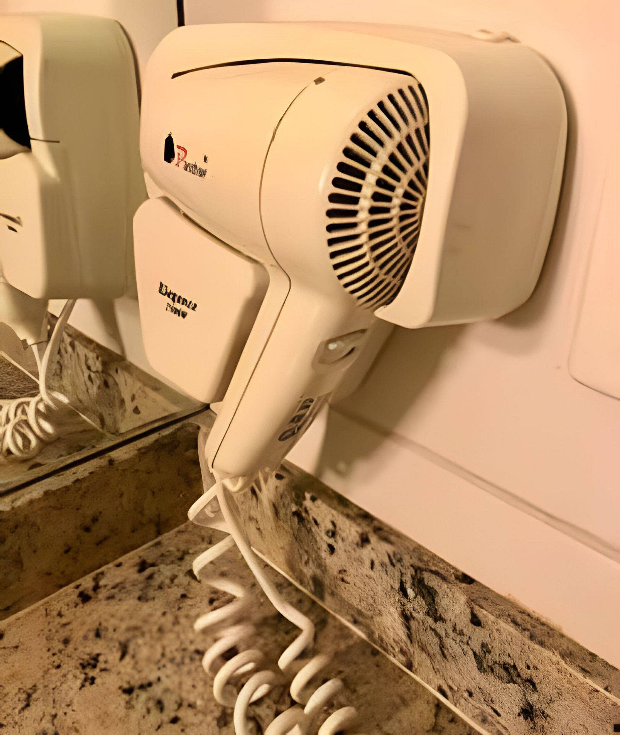 Un secador de pelo fijado a la pared con un cable enrollado.