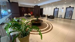 Een moderne lobby met een centraal zitgedeelte, een receptiebalie en een groot raam.
