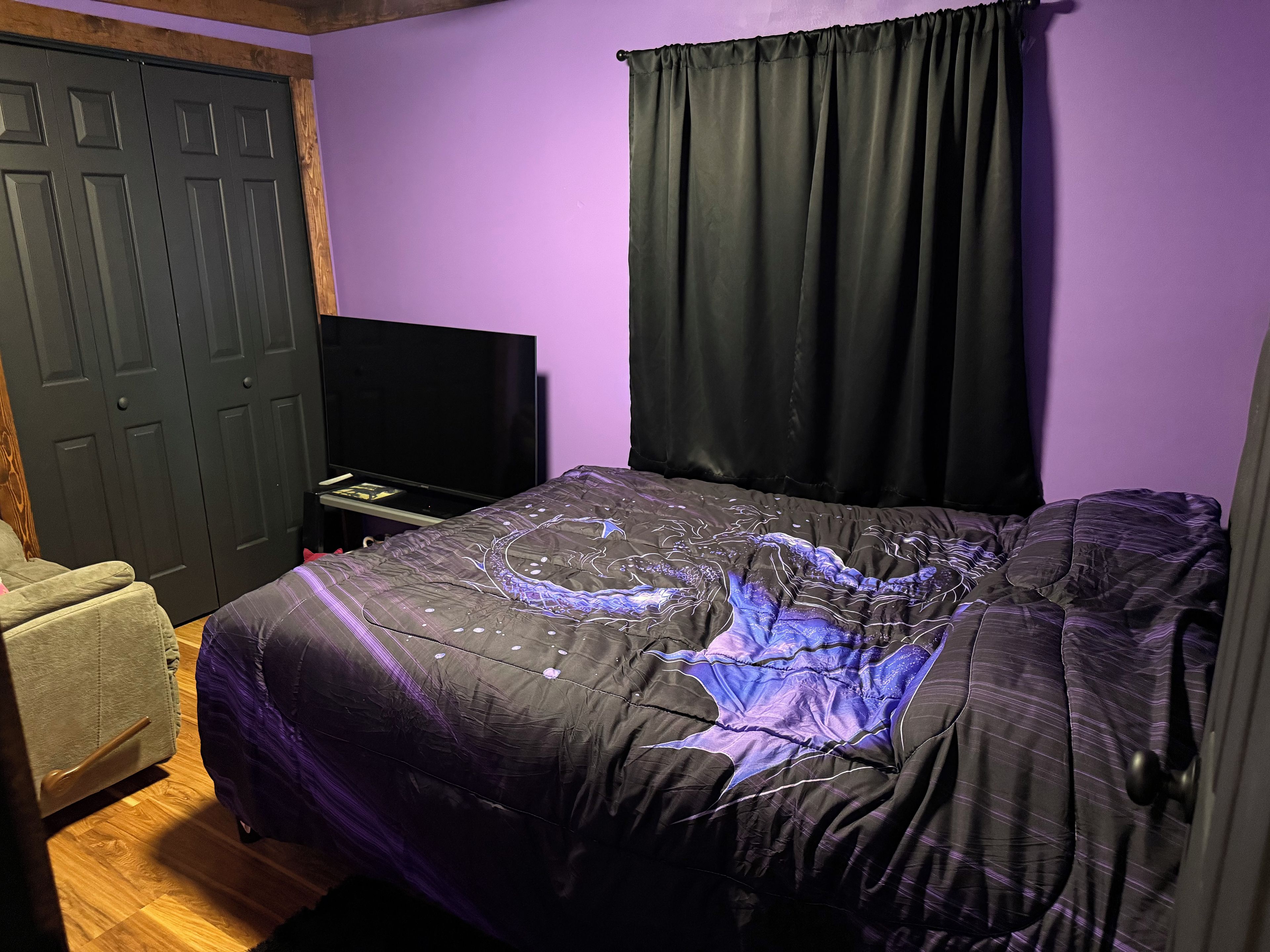 Een slaapkamer met een bed, een televisie, een kledingkast en een stoel.