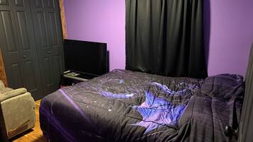 Een slaapkamer met een bed, een televisie, een kledingkast en een stoel.