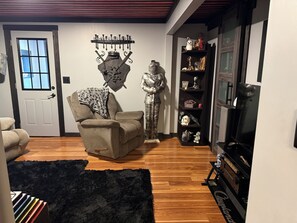 A living room with a sofa, a black furry rug, a decorative metal wall piece, a statue, and a bookshelf.