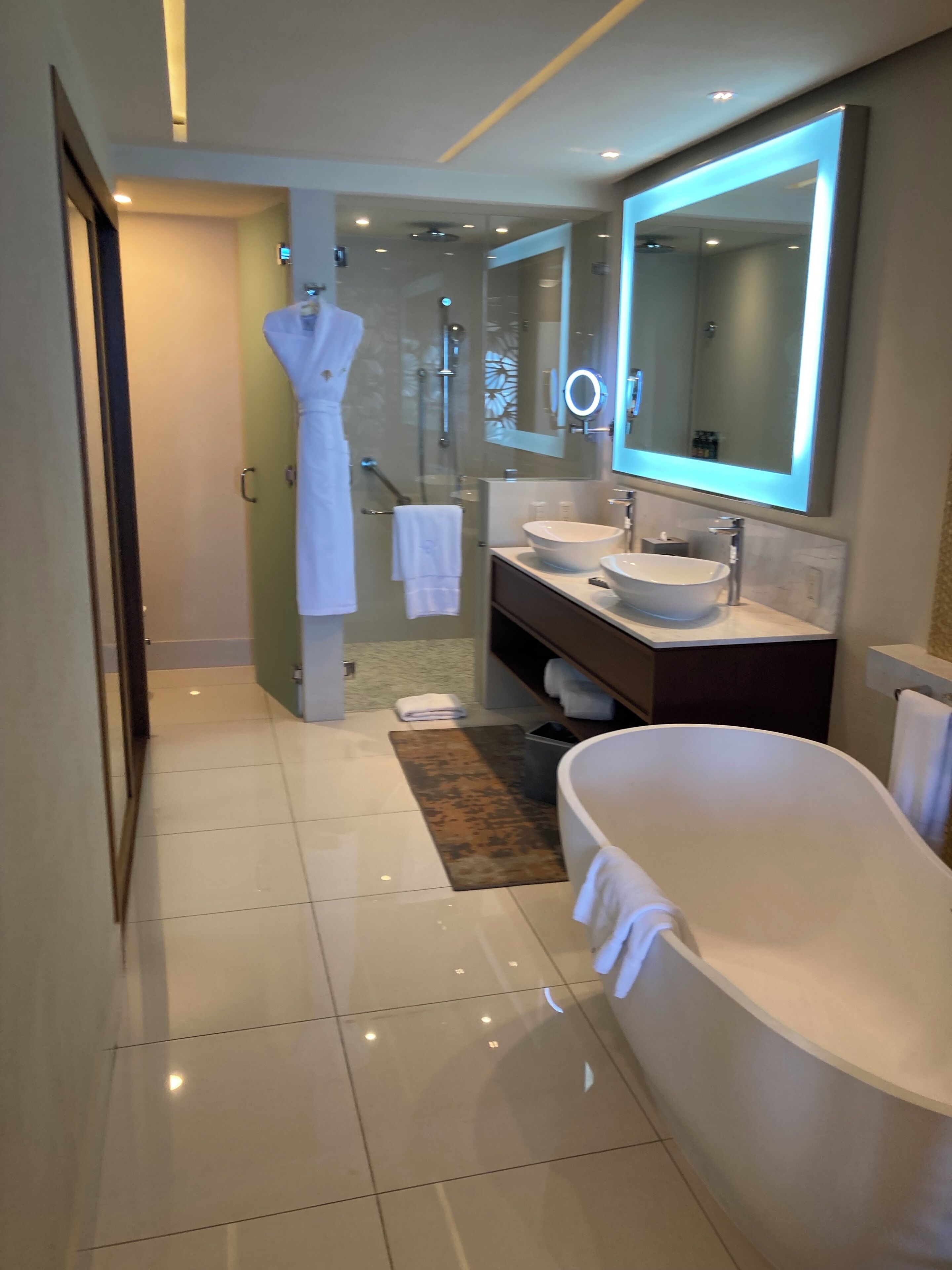 Un baño moderno con una bañera grande, un tocador doble, cabina de ducha de vidrio y ducha a ras de suelo.