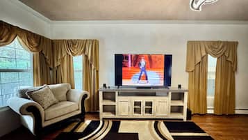 Una sala de estar con televisor, un sofá, un mueble aparador y una alfombra estampada.
