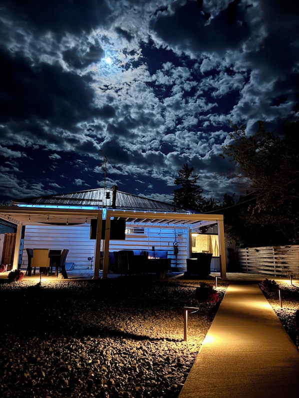 Un espace extérieur abrité, doté d’un foyer, de sièges et d’un chemin menant à un bâtiment.