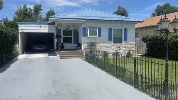 Ein zweistöckiges Haus mit Garage, einer Veranda und einem umzäunten Garten.