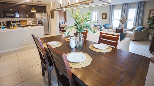 Eine moderne Küche mit Kochinsel, Essbereich mit Holztisch und Stühlen sowie ein Wohnzimmer mit Sofa und Couchtisch.