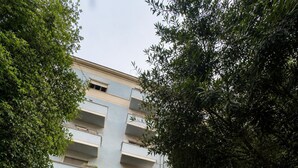 Un immeuble à plusieurs étages doté d’une entrée centrale, de balcons et d’un chemin pavé menant à l’entrée.