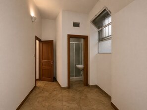 A hallway with a wooden door, a bathroom with a sink, and a window with frosted glass. - San Lorenzo Guest House (Roma)