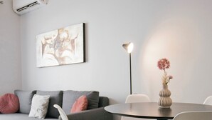 Ein modernes Wohnzimmer mit einem grauen Sofa, weißen Sesseln, einem runden Tisch und einer Stehlampe.