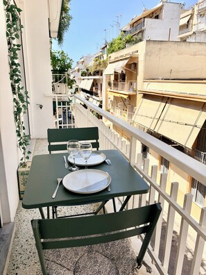 Ein Balkon mit einem Tisch, der für zwei Personen gedeckt ist, inklusive Teller, Besteck und Weingläsern.