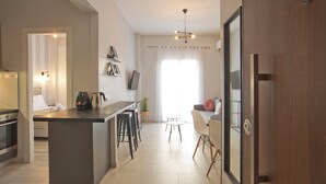 Eine moderne Küche mit Kochinsel, ein Essbereich mit Tisch und Stühlen sowie ein Wohnbereich mit Sofa und Fernseher.