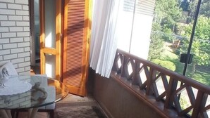 Un balcon avec une balustrade en bois, une table en verre avec des chaises et un tapis à motifs.