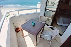 Un balcón con mesa y sillas, con vista a la playa.