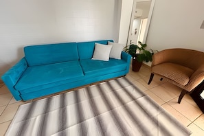 A room with a blue sofa, a brown armchair, and a striped rug. - SHB Horizonte Azul Refúgio Inesquecível (Santos)