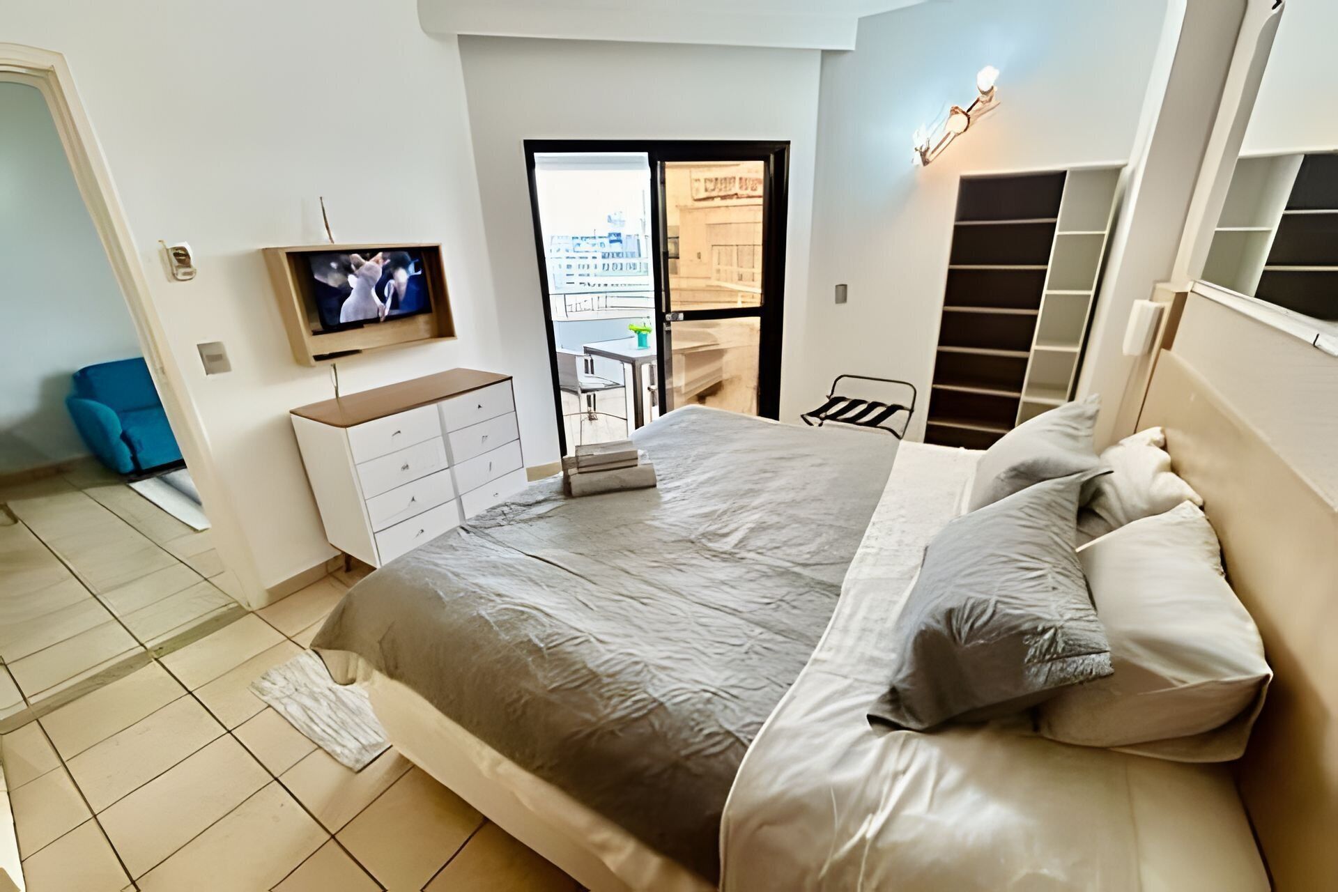 A bedroom with a bed, a TV, a desk, and a chair.