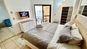 A bedroom with a bed, a TV, a desk, and a chair.