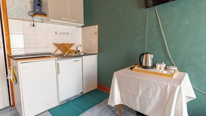 A compact kitchen with a sink, a coffee maker, and a table with a white tablecloth. - Cozy, centrally located, quiet, and fully equipped studio—ideal for medical treatment, tourism, or business trips (Bourbonne-les-Bains)