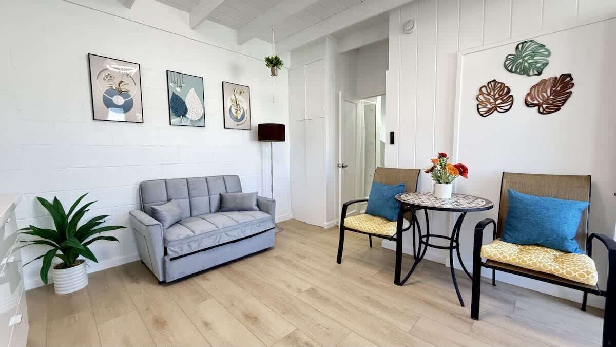 A modern living room with a grey sofa, two armchairs, a small round table, and a potted plant.