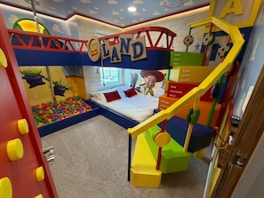 Ein Kinderspielzimmer mit Etagenbett, Ballgrube und bunten Spielgeräten.