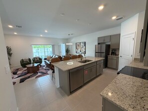 A modern kitchen with a central island, built-in appliances, and a dining area with a sofa and chairs. - 5 BD/ 4.5 BA/ New! Posner Reserve (125 PS) (Davenport)