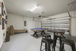 A room with a pool table, stools, a foosball table, and a projector. - 5 BD/ 4 BA/ Solterra (7247OL) (Davenport)