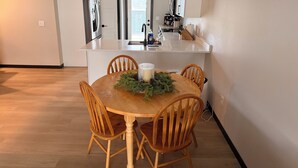 Une cuisine moderne avec des meubles blancs, un îlot central et un coin repas comprenant des chaises et une table en bois.